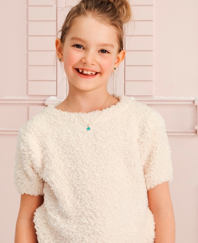 A girl in a beige T-shirt showing off pendants